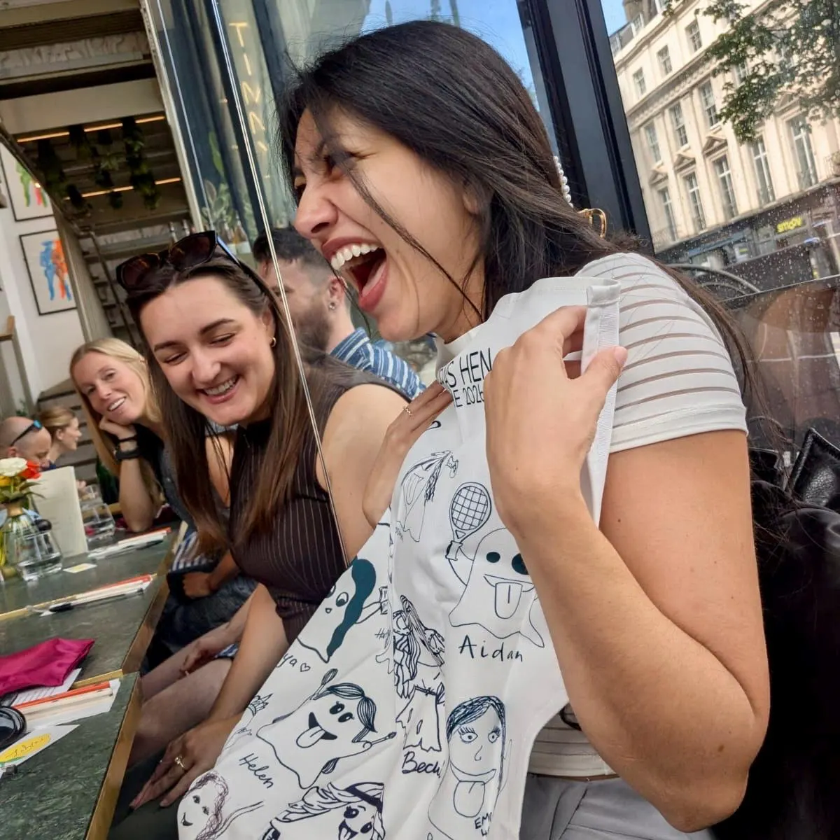 Guest laughing while holding a doodle-printed garment at a celebration